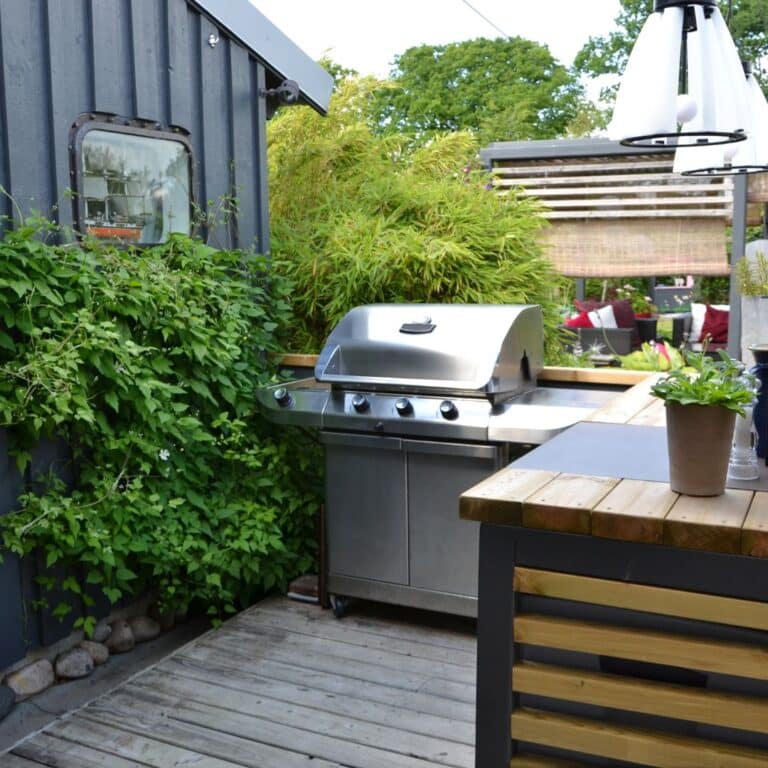 Compact outdoor kitchen setup with a stainless steel grill and wooden counter designed by professional outdoor kitchen contractors.