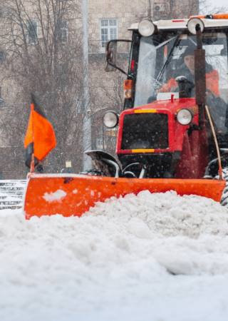 Commercial snow removal tractor clearing heavy snow from city streets to ensure safe access during winter storms.